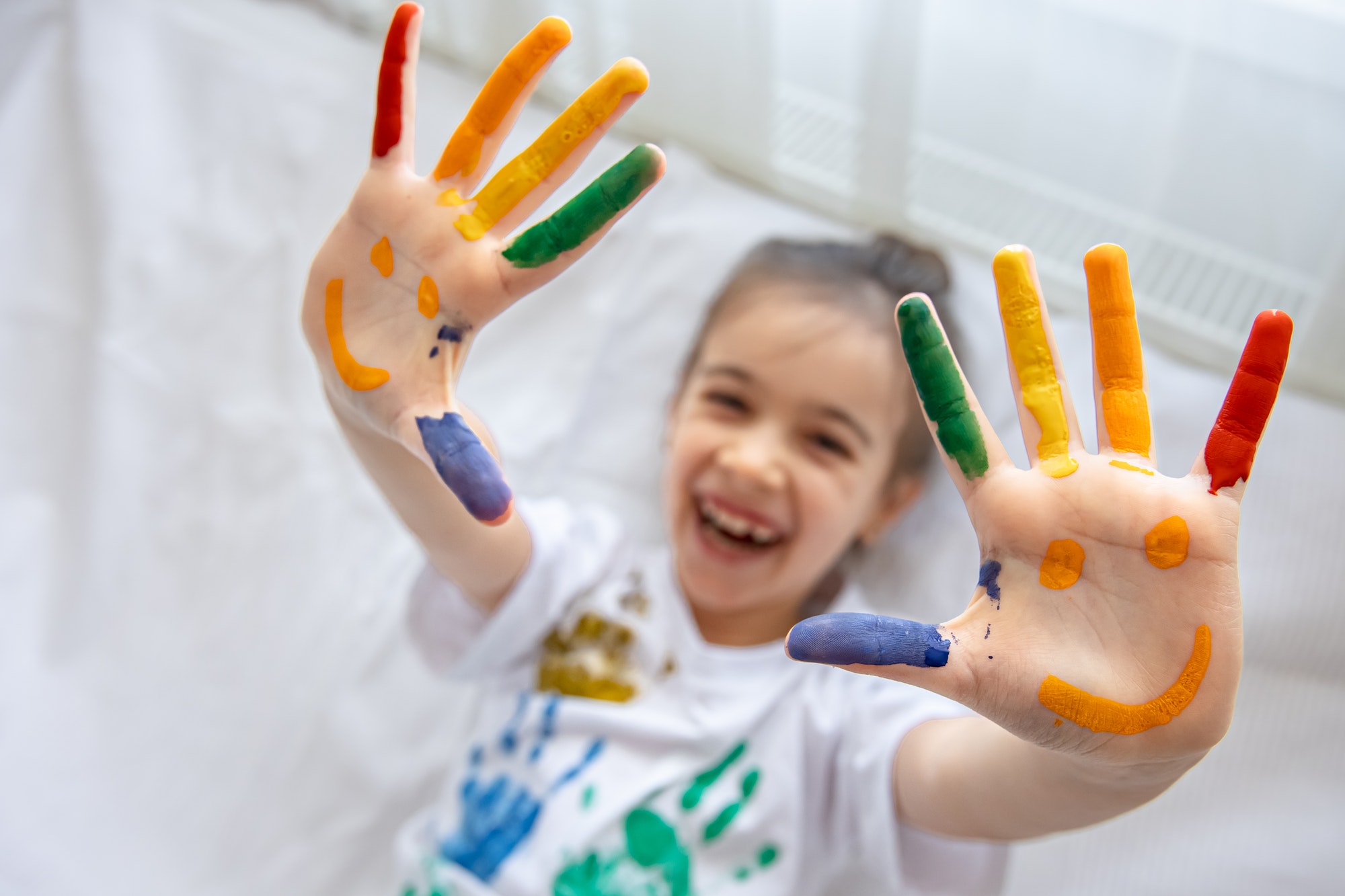 Close up of colored palms of a child, painted with paints.